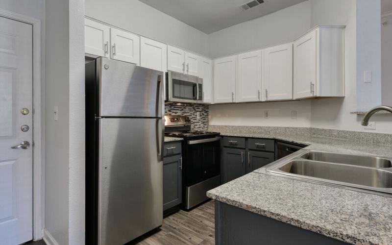 Spacious kitchens with thoughtful details a kitchen with white cabinets a fridge a stovetop and a sink