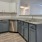 a kitchen with white cabinets granite countertops a fridge a sink and a dishwasher